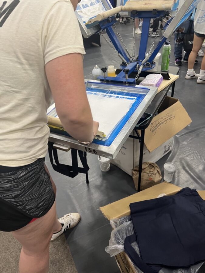 A person printing a t-shirt with a screen printing machine